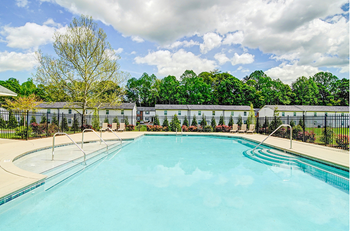 A swimming pool with a fence and trees in the background